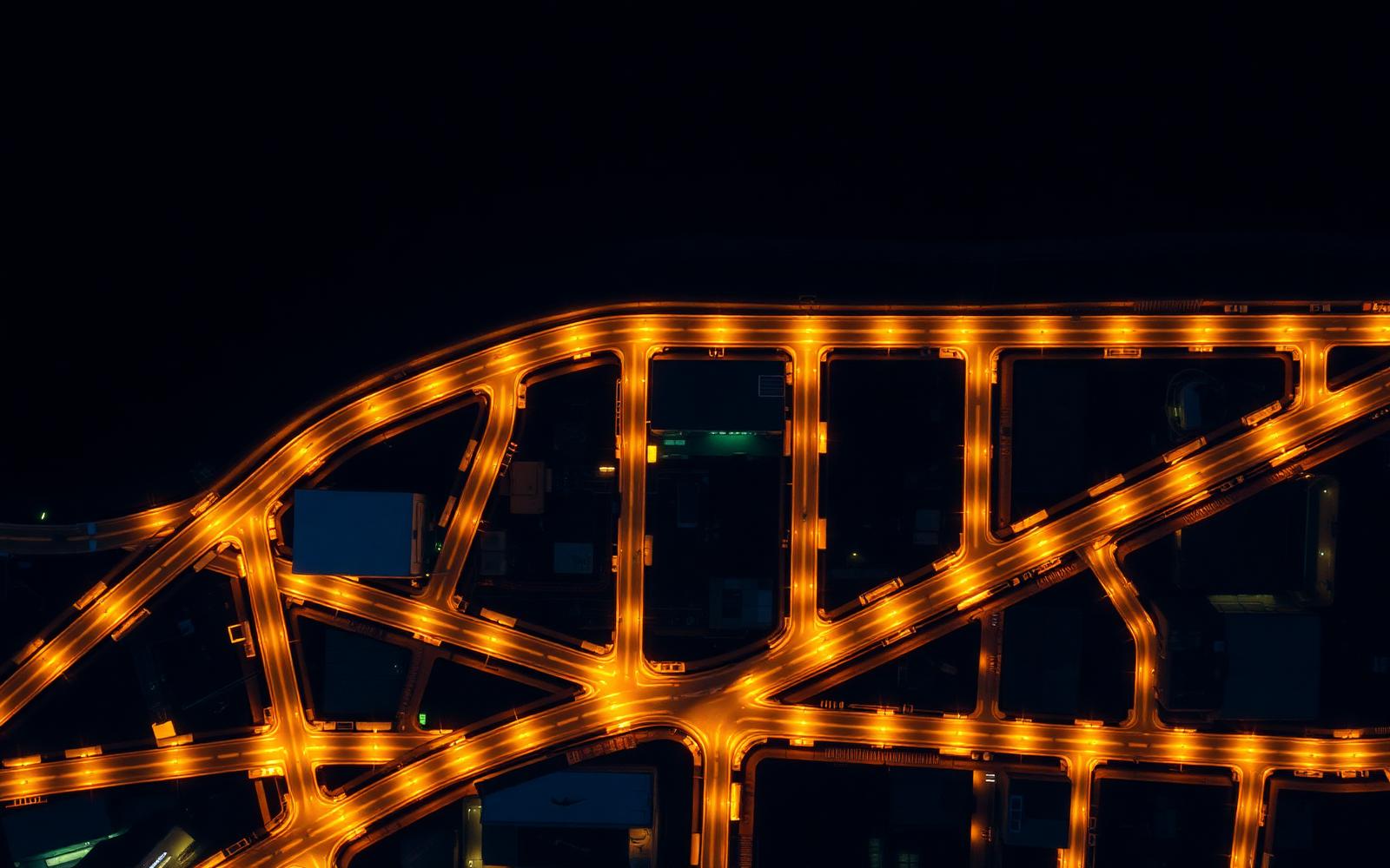 Aerial night view of a warm amber-lit city road network on dark ground