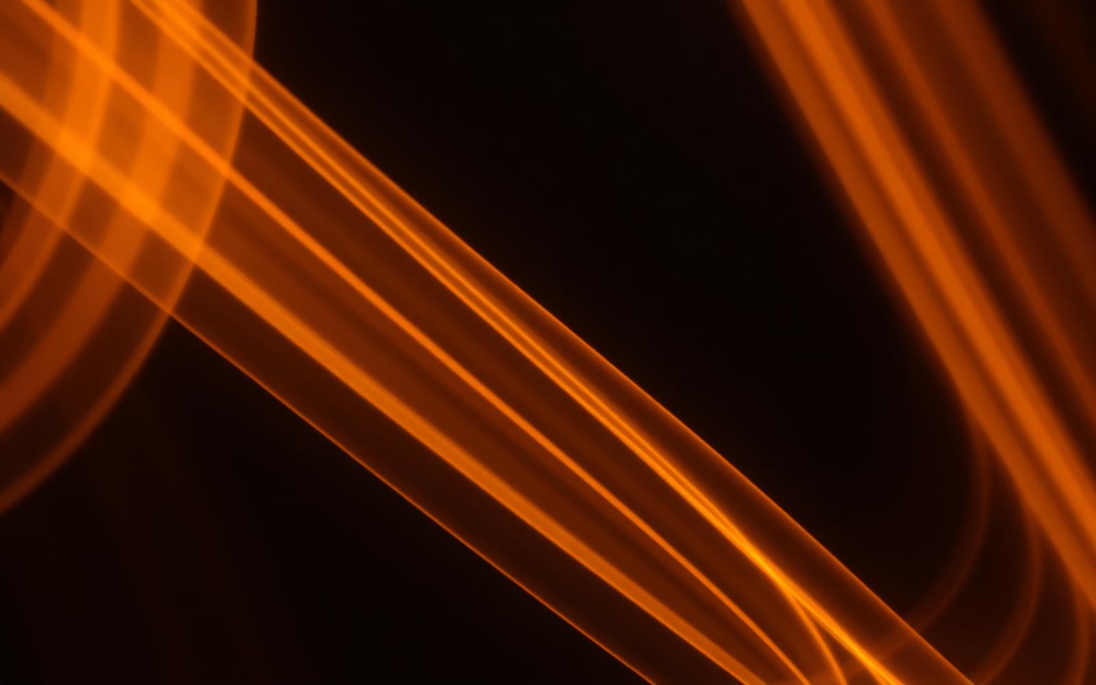 Long-exposure warm amber light trails streaking upward through darkness